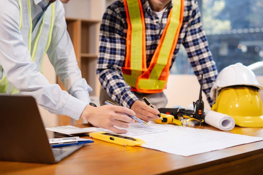 Professional engineers in safety vests planning a building site, emphasizing industrial contracting and construction management services.